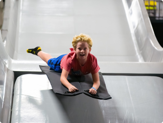 child going down slide on mat